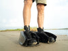 Man wearing Mudder Boots over standard shoes on wet sand