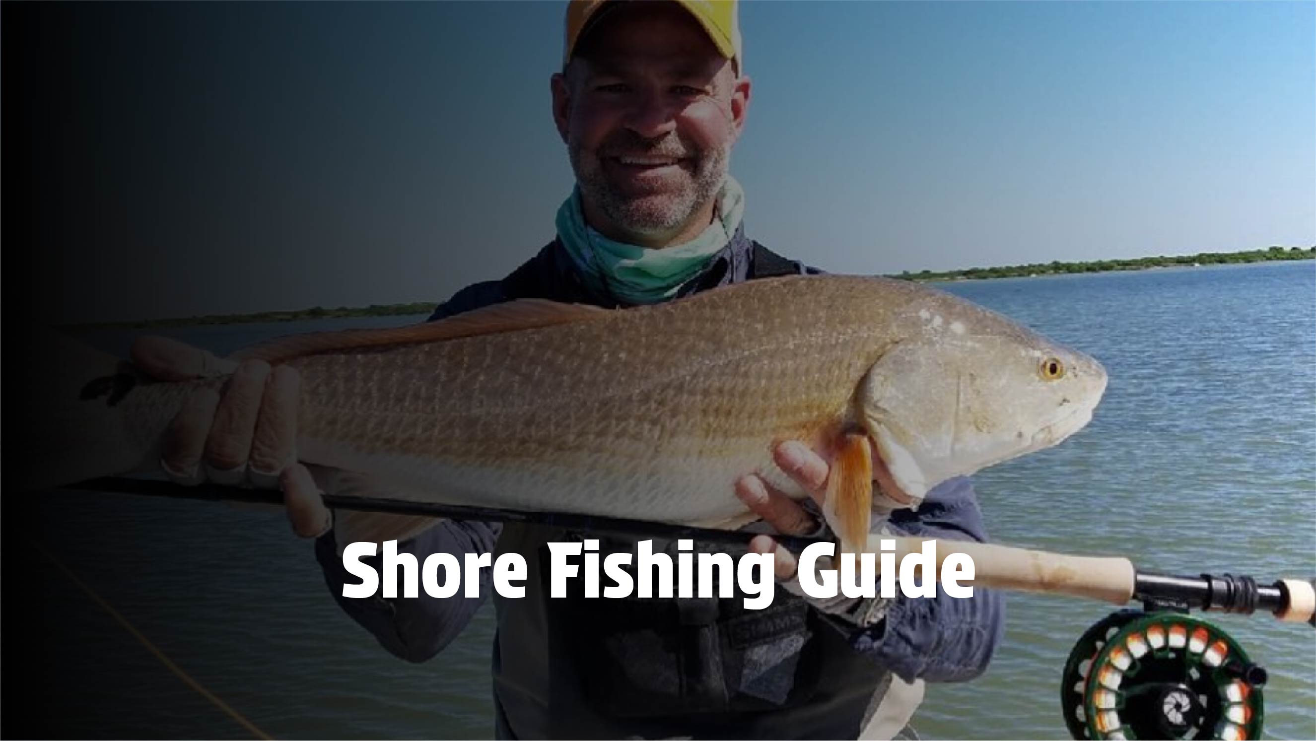A happy angler holding a large redfish caught while shore fishing.